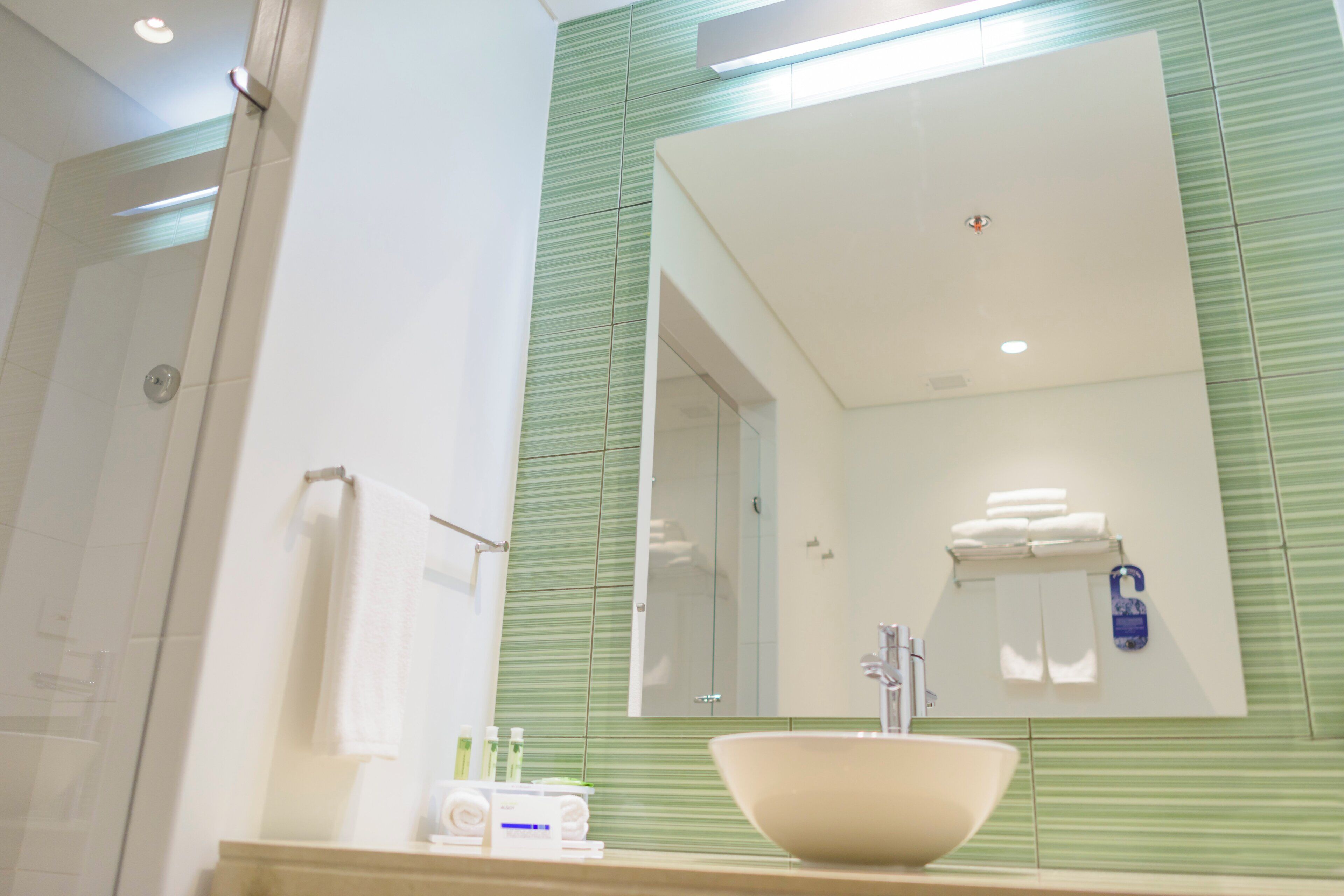A bathroom with a large mirror, a sink, and a shower.