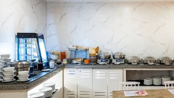 Een moderne hotelkeuken met marmeren wanden, een buffetopstelling en een koffieapparaat.