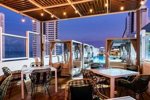 A rooftop bar with wicker furniture, large windows, and a view of the city skyline. - Holiday Inn Express Cartagena Bocagrande by IHG (Cartagena)