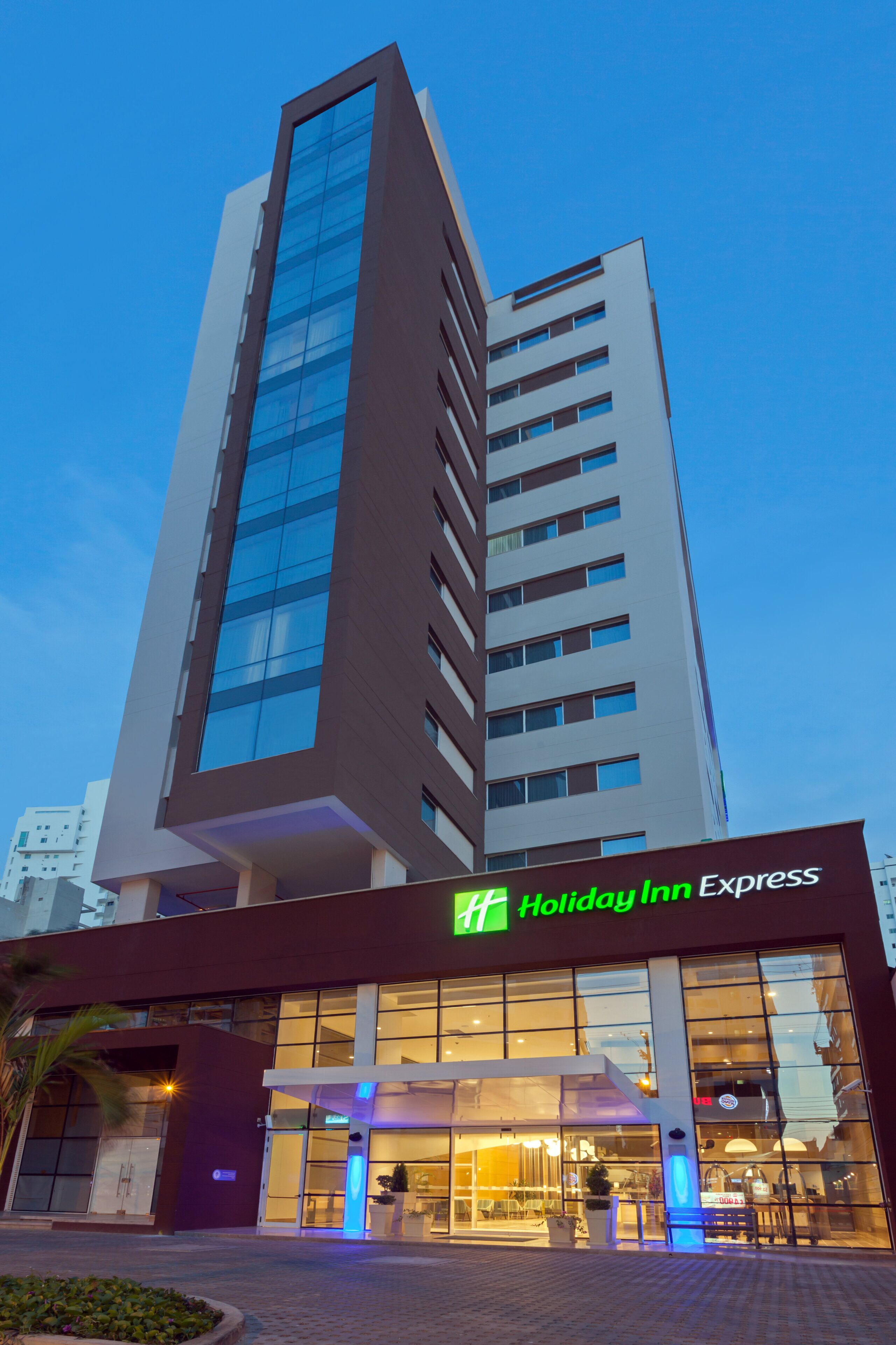 A modern hotel building with a prominent glass facade and a Holiday Inn Express sign.