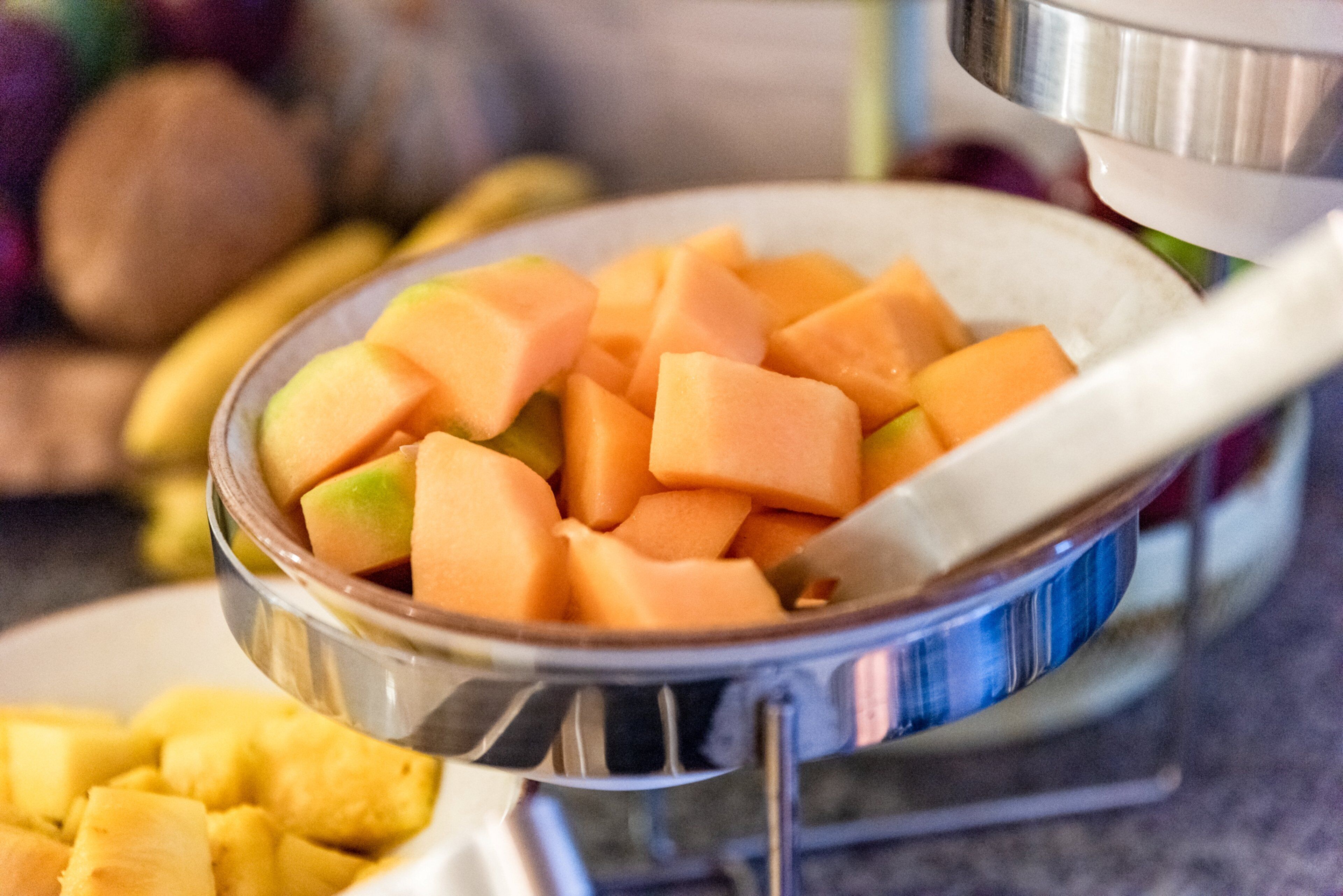A bowl of cubed melon, likely cantaloupe, with a spoon inside.