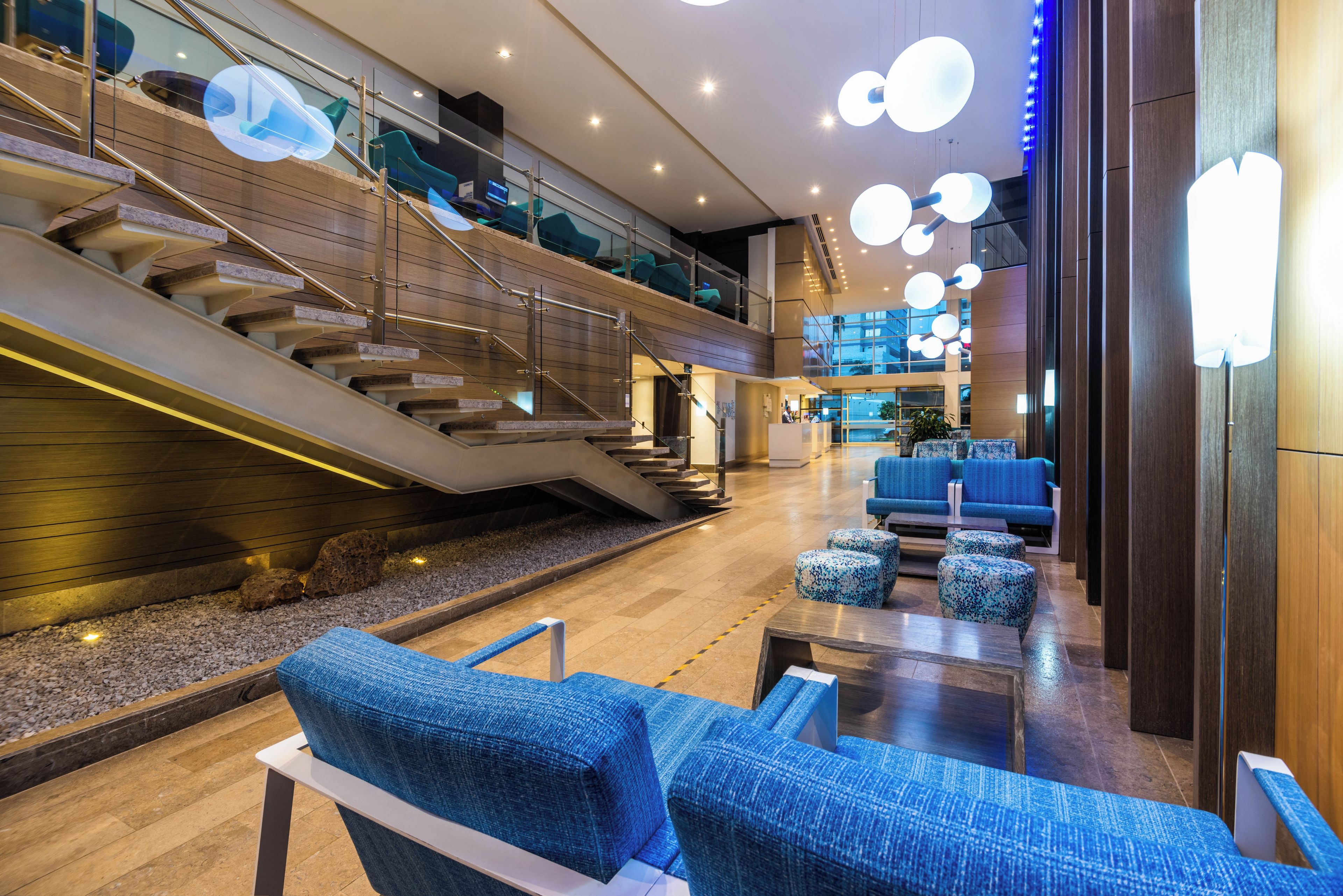 A modern lobby with a staircase, seating area, and a reception desk.