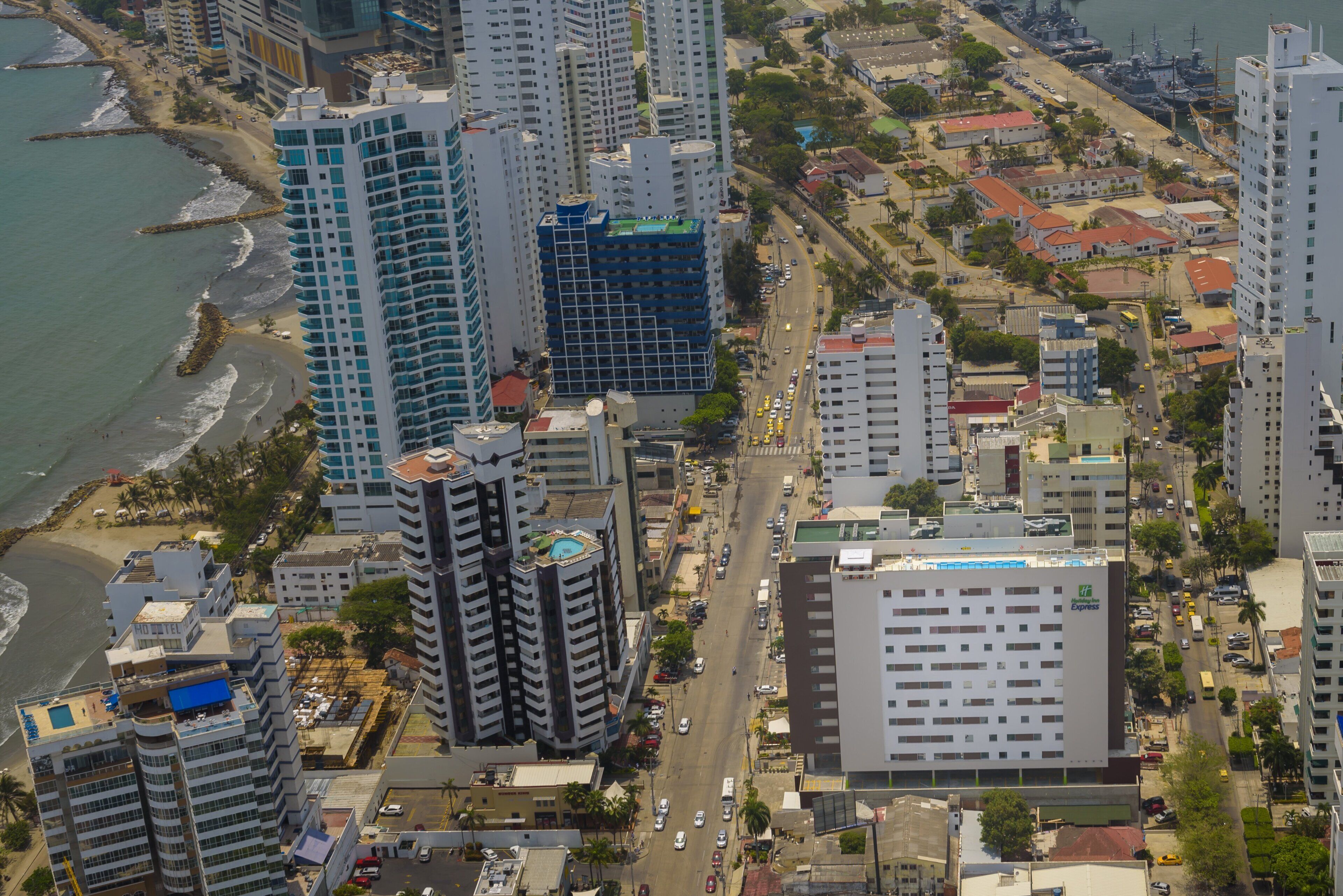 A high-rise hotel with multiple floors, a swimming pool, and a view of the cityscape.