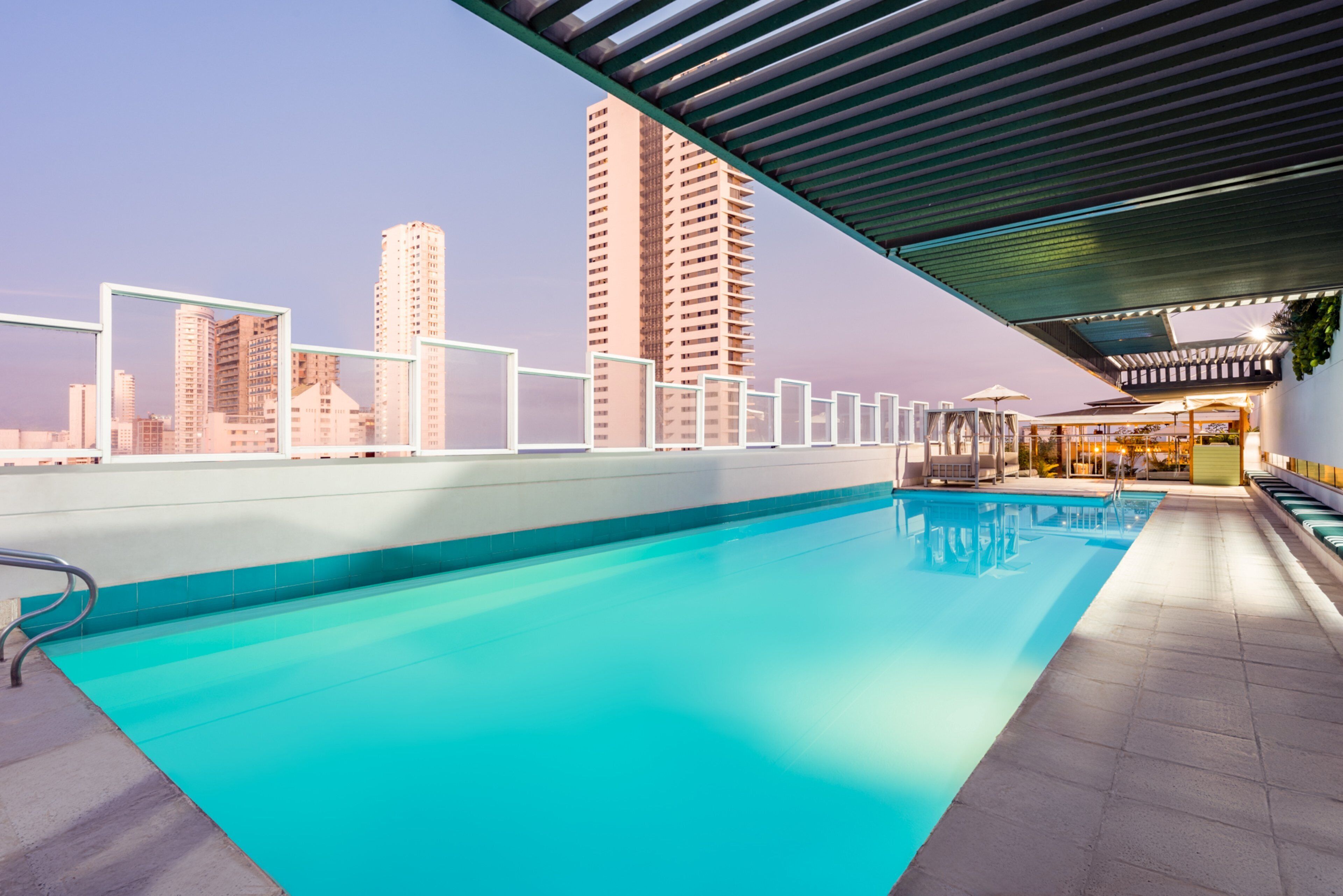 Une piscine sur le toit offrant une vue sur la ville, entourée d’immeubles de grande hauteur.