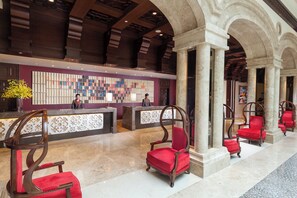 A hotel lobby with a reception desk, red upholstered chairs, and a decorative wall. - Holiday Inn Airport Guangzhou by IHG (Guangzhou)