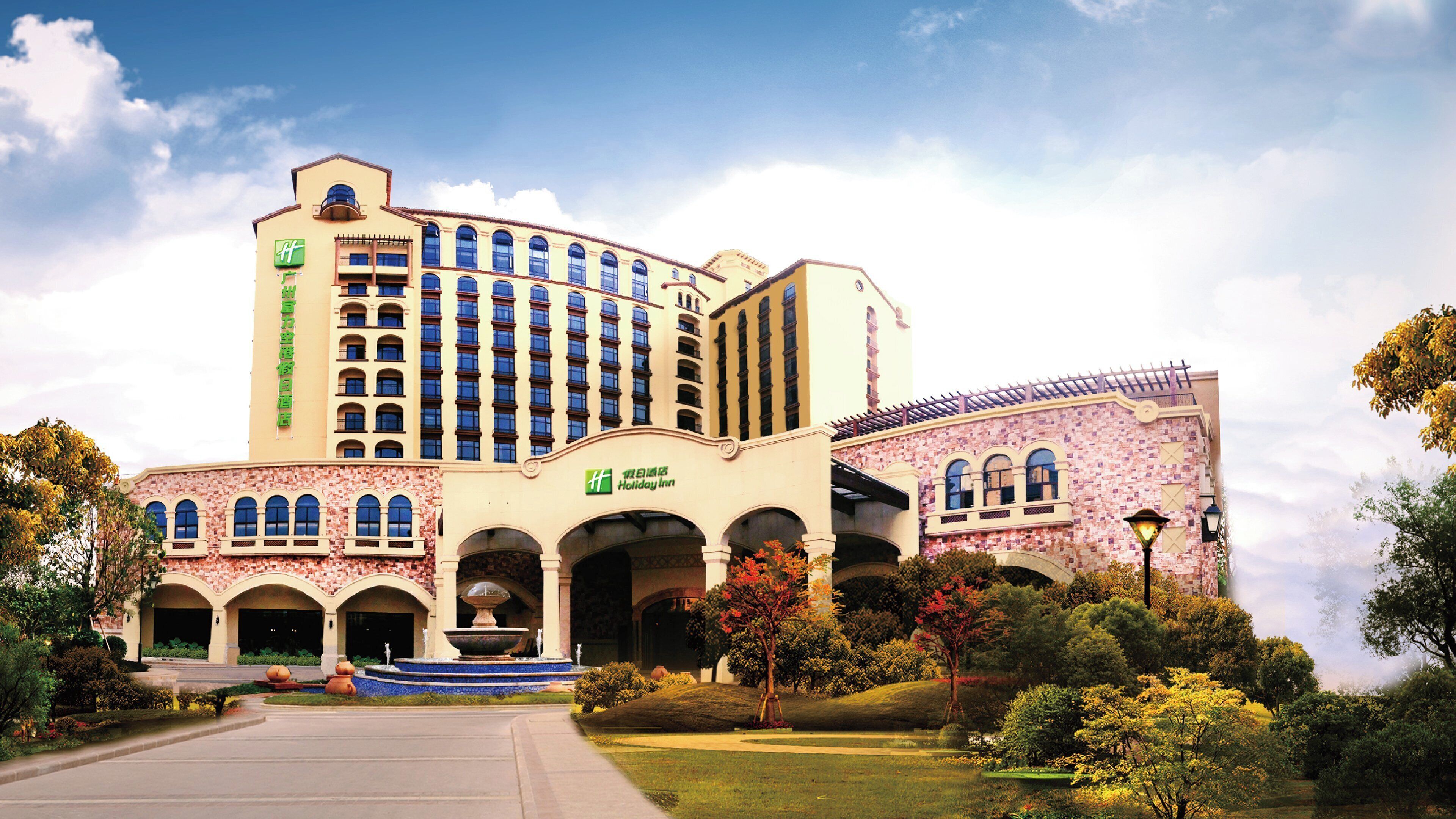 A large hotel with multiple floors, a central courtyard with a fountain, and a Holiday Inn sign.