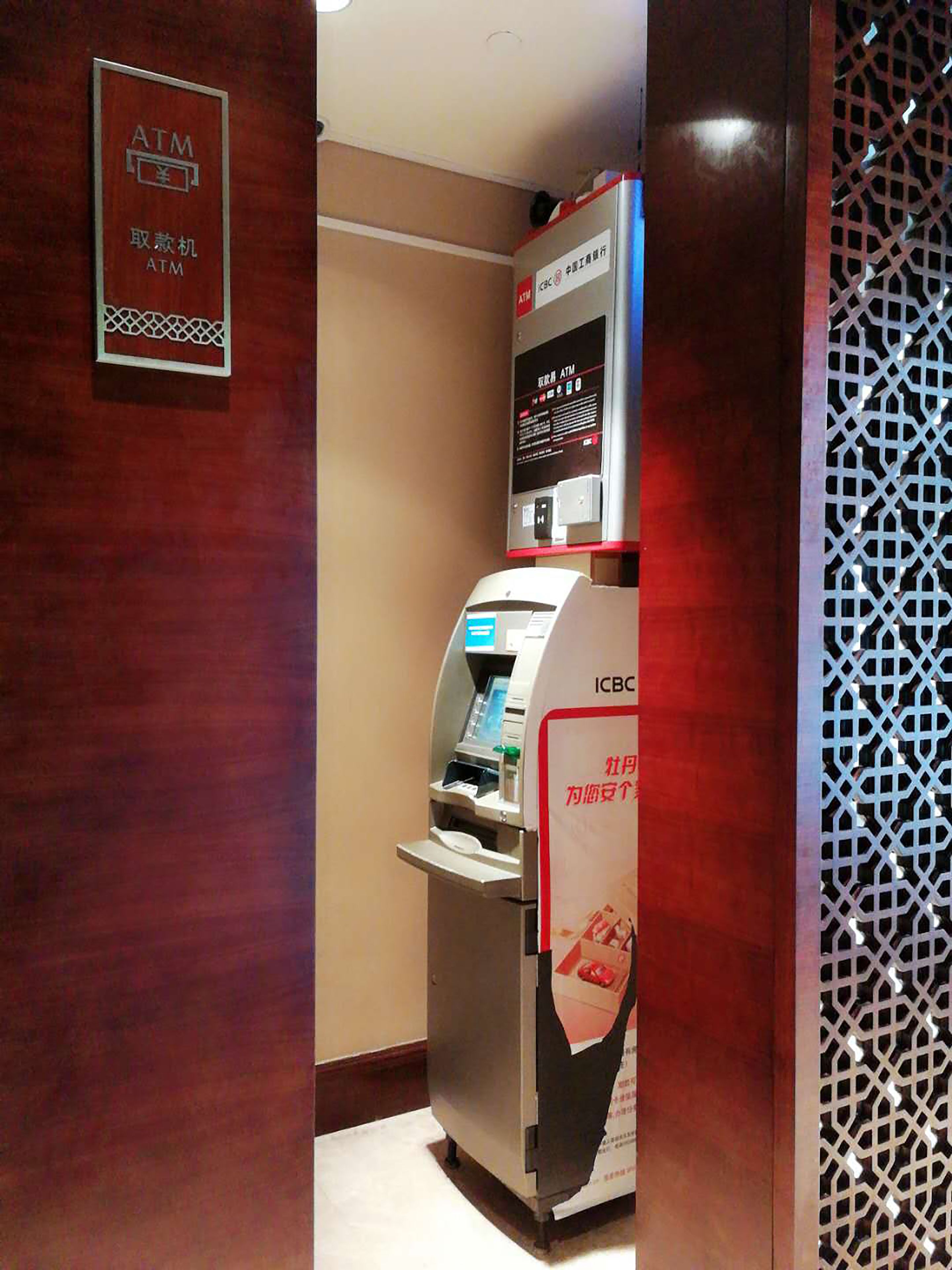 An ATM machine with a sign above it and a decorative panel on the wall.