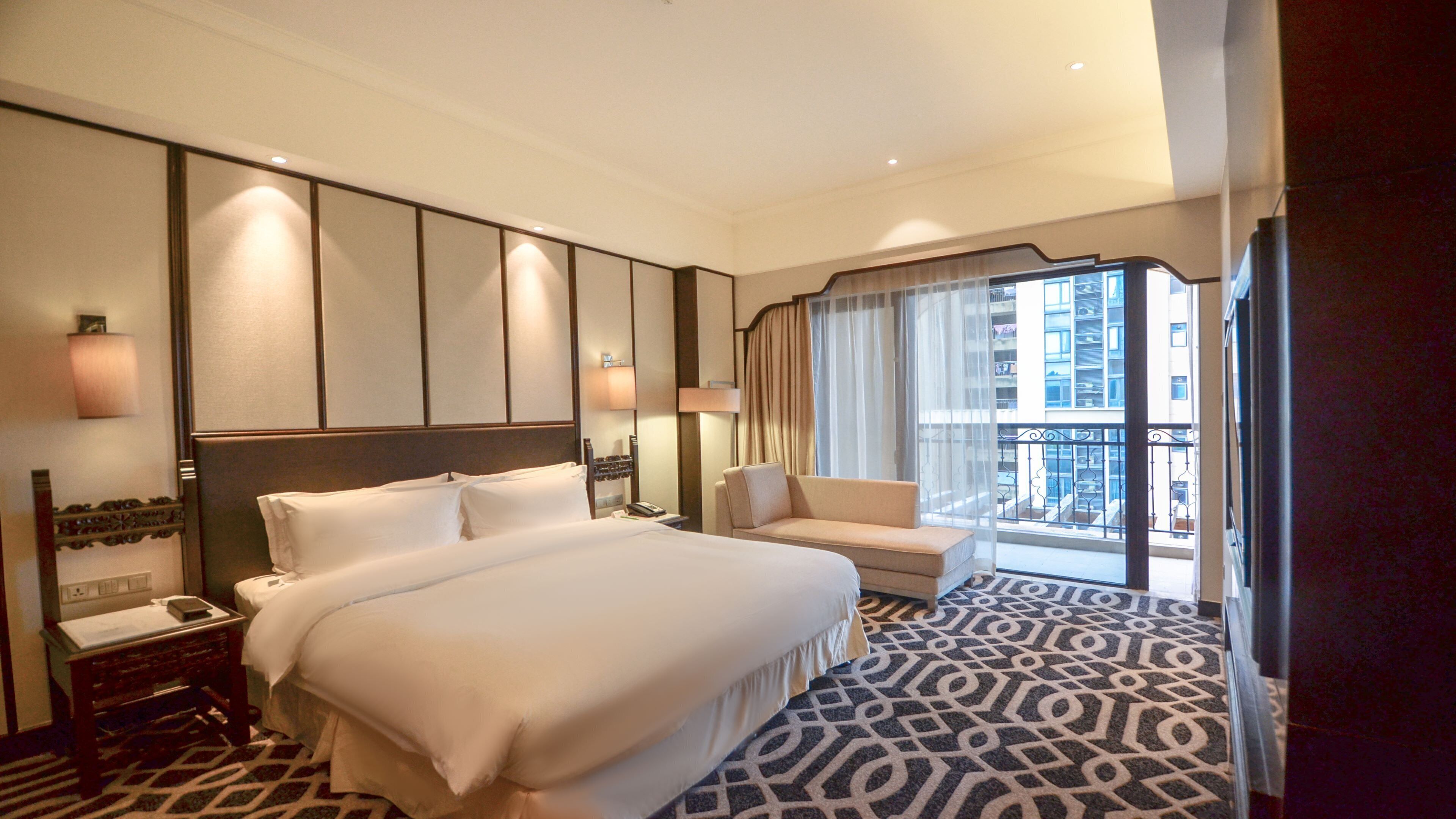 Une chambre d’hôtel avec un grand lit, un canapé, un bureau et une fenêtre donnant sur des immeubles.