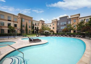 A swimming pool with lounge chairs and a basketball court, surrounded by apartment buildings. - Staybridge Suites Carlsbad by IHG (Carlsbad)