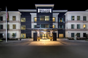 A Staybridge Suites hotel with a modern facade, multiple entry points, and a flagpole. - Staybridge Suites Carlsbad by IHG (Carlsbad)