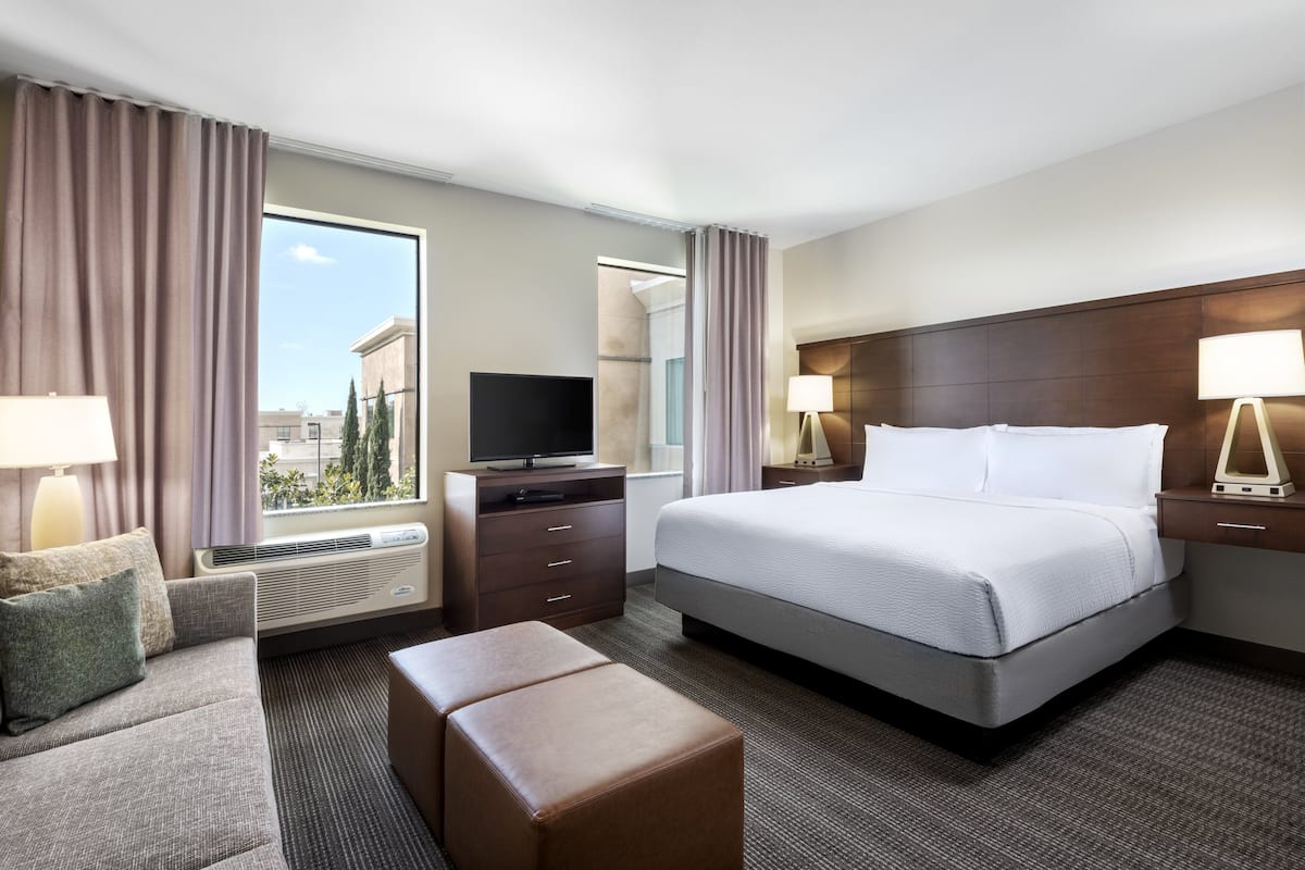 Una habitación de hotel con una cama grande, un sofá, un televisor y un escritorio con una lámpara.