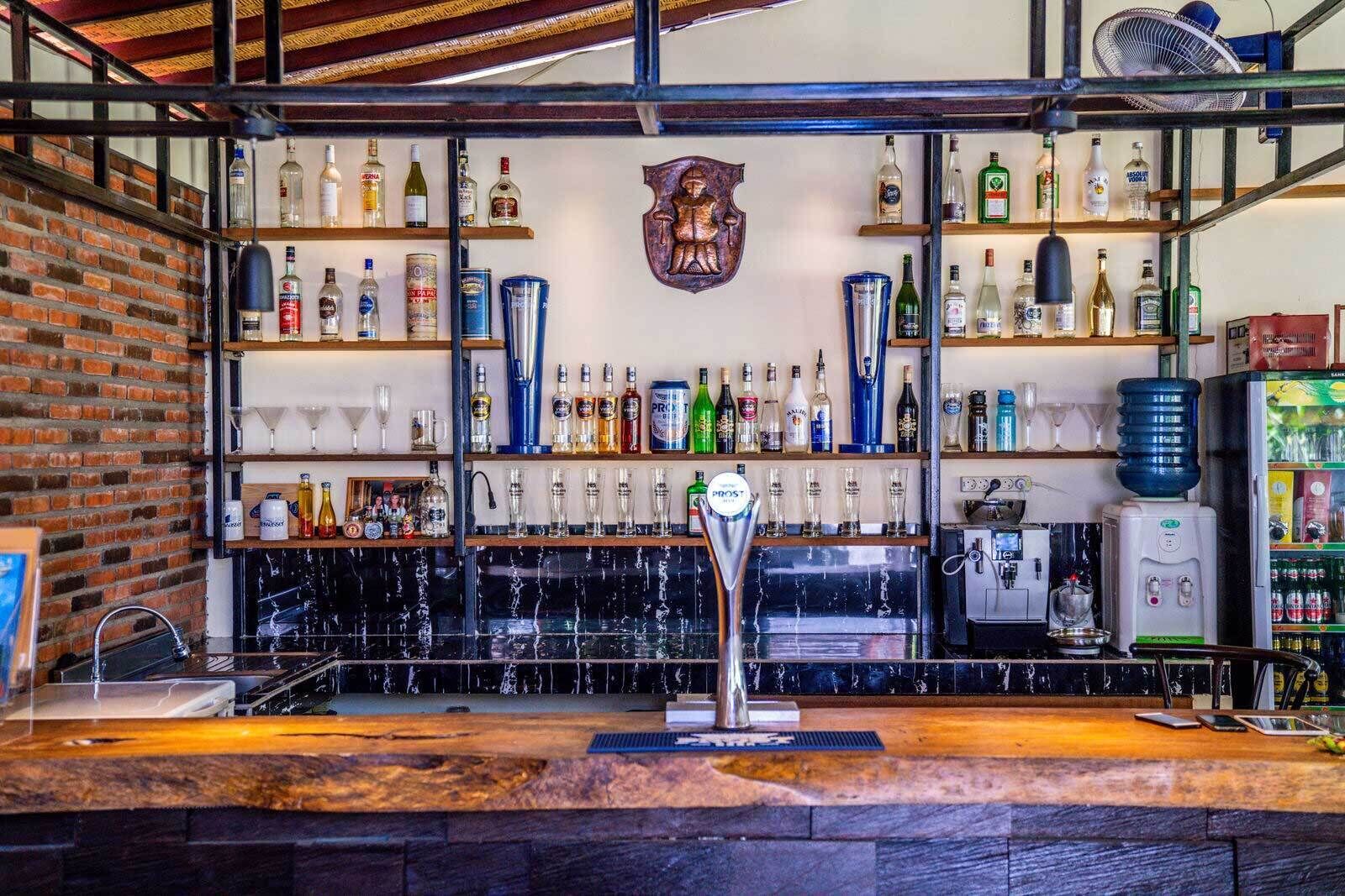 En bar med en vägg av tegelstenar, hyllor fyllda med spritflaskor, en ölkran och en vattenautomat.