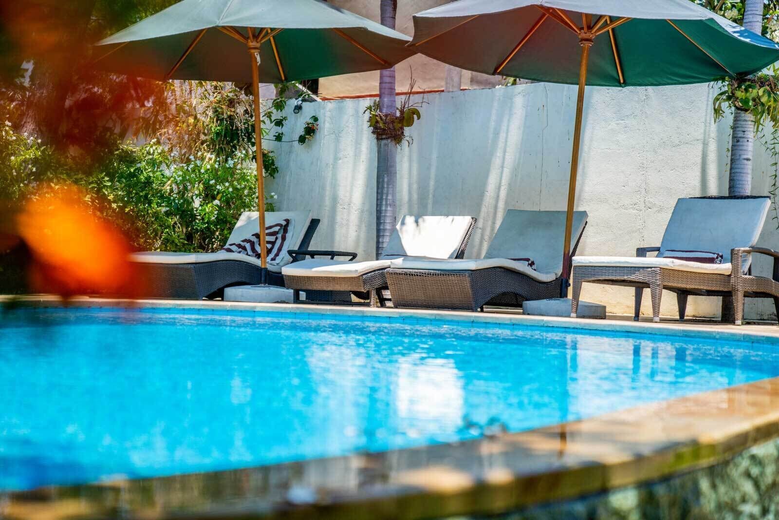 A pool area with lounge chairs and umbrellas.