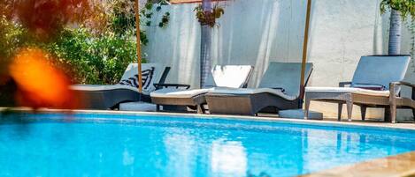 A pool area with lounge chairs and umbrellas.