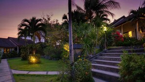 A tropical resort with a well-maintained garden, palm trees, and a staircase leading to a building. - Ocean Sun Dive Resort (Tulamben)