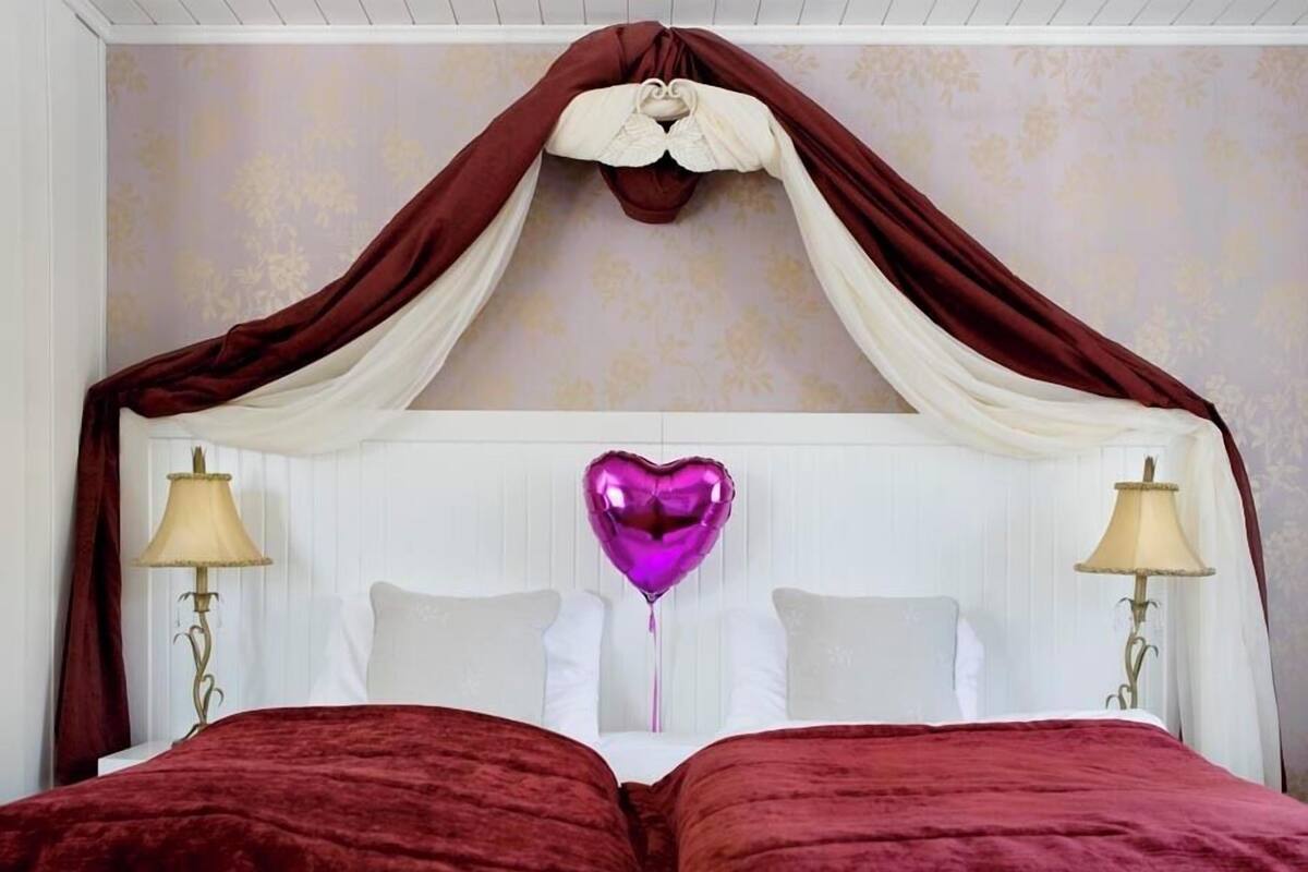 Una cama con dosel, dos lámparas de noche y un globo con forma de corazón.