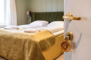 Un lit avec une tête de lit verte, une poignée de porte en bois et un trou de serrure orné d’un porte-clés en forme d’arbre.