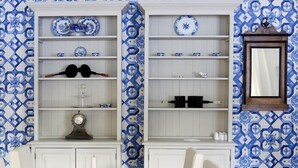 Un comedor con una mesa de madera y sillas blancas, rodeado de armarios con azulejos de diseño azul.
