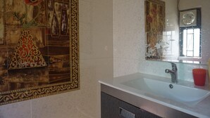 Une salle de bain avec un mur recouvert de carreaux décoratifs, un lavabo blanc et un miroir.