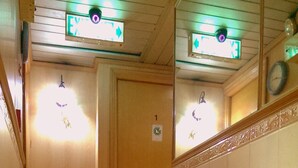 Un couloir avec une porte en bois, une pile de papier toilette et une horloge murale.