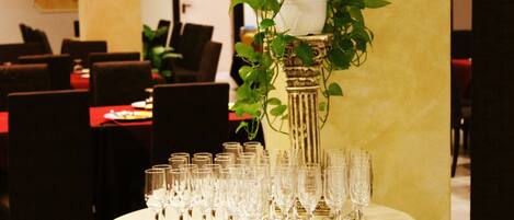 Une table avec plusieurs verres à vin disposés en rangées, une plante en pot et une nappe.