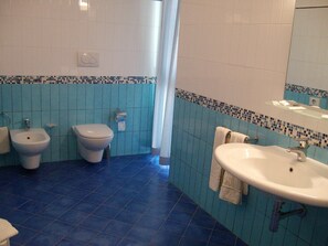 A bathroom with a bidet, toilet, sink, and a mirror.