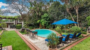 A backyard with a swimming pool, lounge chairs, and a pergola.