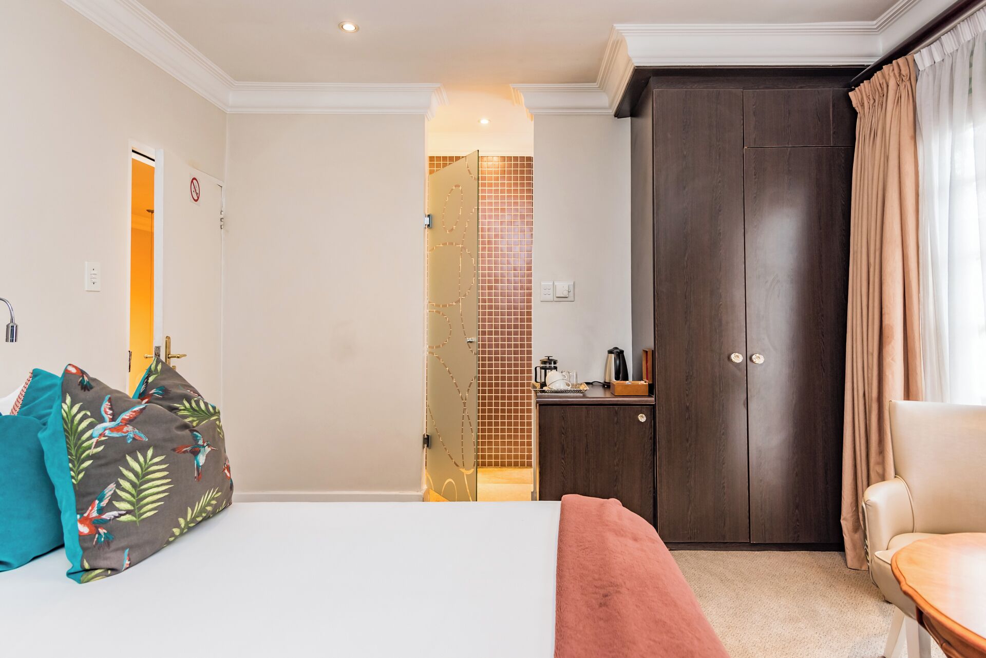 A hotel room with a bed, a desk, a wardrobe, and a chair.
