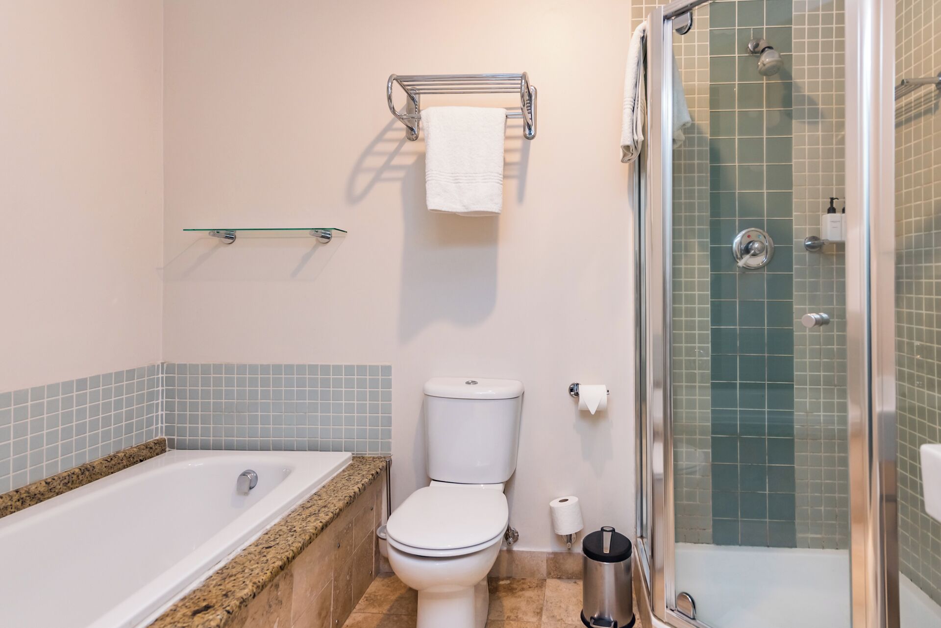 A bathroom with a bathtub, toilet, and glass-enclosed shower.