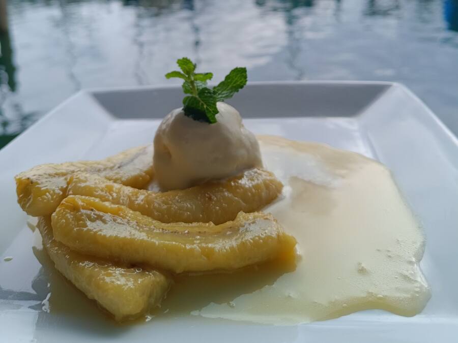 A dessert with a mint garnish on a white plate, with a marina and boats in the background.