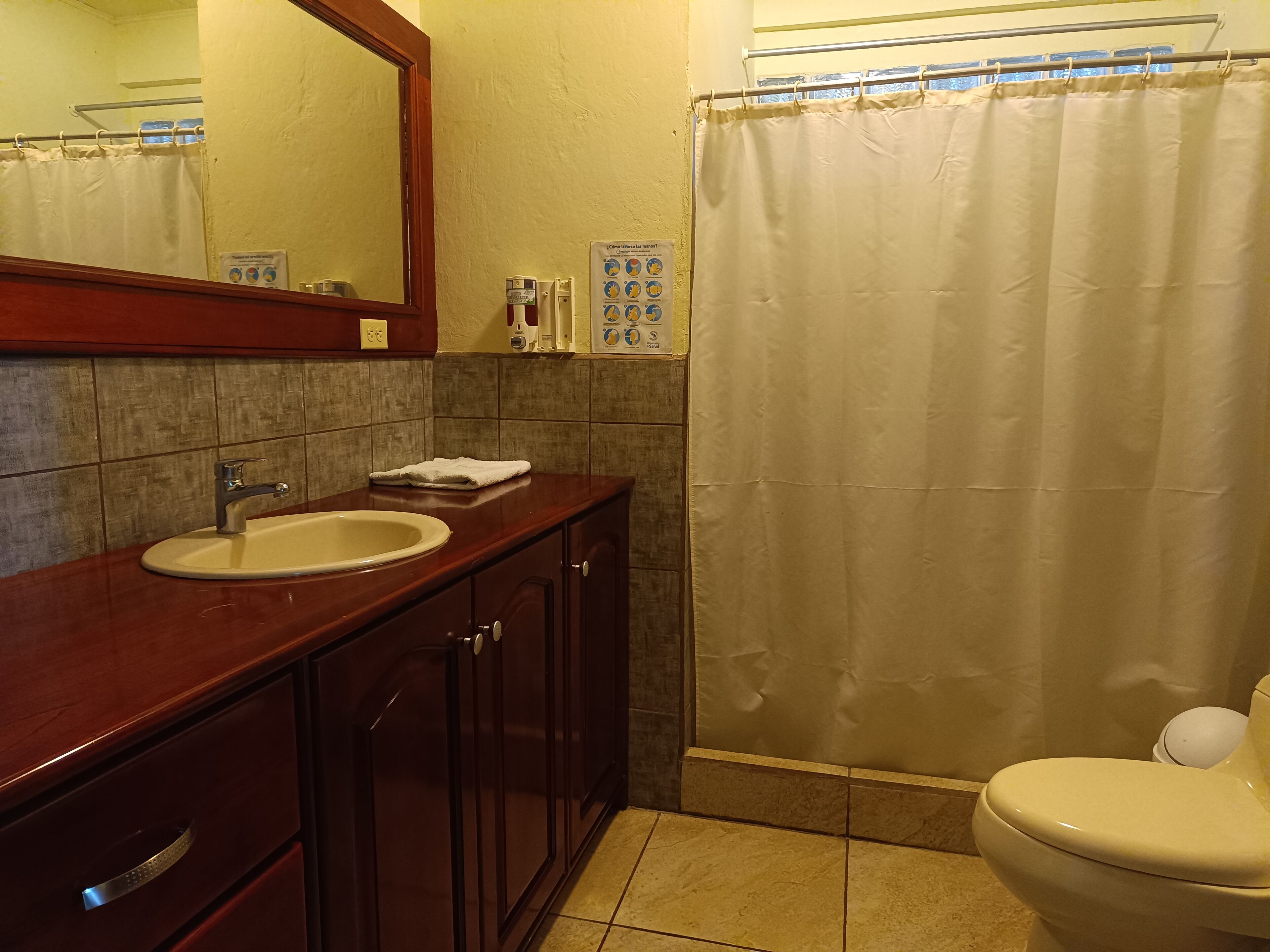 Un baño con lavamanos, espejo, armarios y retrete.