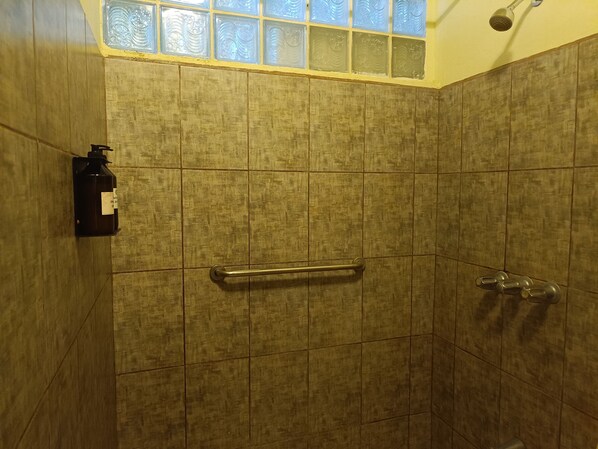 A shower with a glass door, a towel rack, and a soap dispenser.