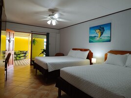 Habitación de hotel con dos camas, un ventilador de techo, un cuadro de un pájaro y vistas a un cuarto amarillo con kayaks.