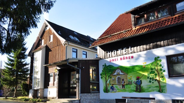 Een gebouw met een muurschildering van landschappen, een bankje en een heldere lucht.