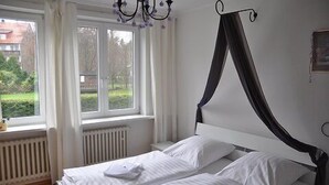 Een slaapkamer met een bed, een raam en een radiator.