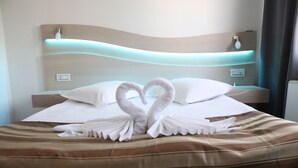 A hotel room with a bed featuring a heart-shaped towel arrangement and a modern headboard with integrated lighting. - SCALA Bed & Breakfast (Vodice)