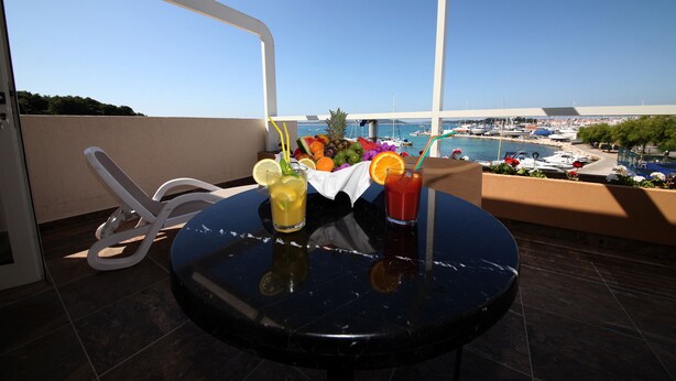 A balcony with a table set for two, featuring a fruit and drink arrangement, overlooking a marina with boats. - SCALA Bed & Breakfast (Vodice)