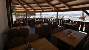 An outdoor restaurant with wooden tables and chairs, overlooking a marina with boats. - SCALA Bed & Breakfast (Vodice)