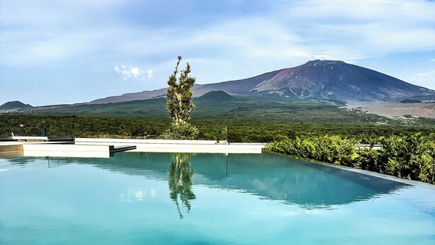 Una piscina azul cristalina con vista a las montañas.
