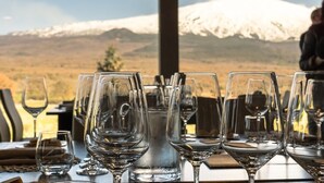 Una mesa dispuesta con copas de vino y una jarra de agua, con vistas a una cadena montañosa nevada.