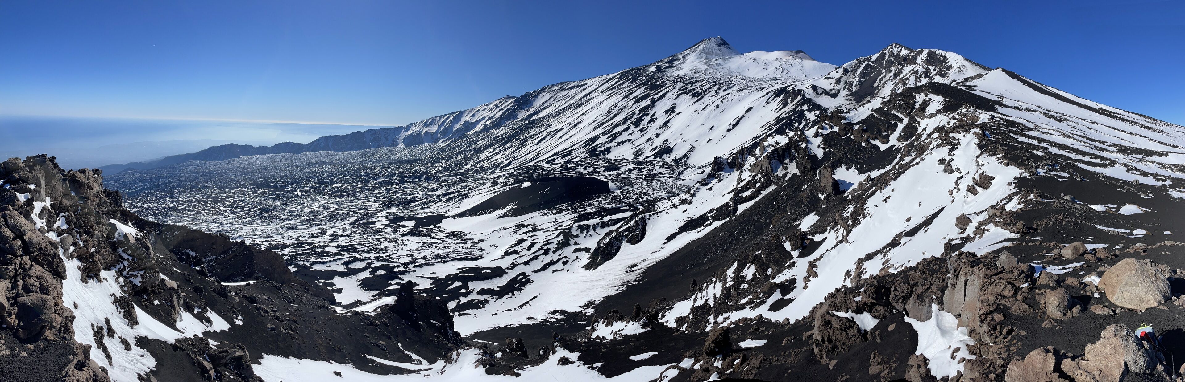 Una montaña con laderas nevadas y terreno rocoso.