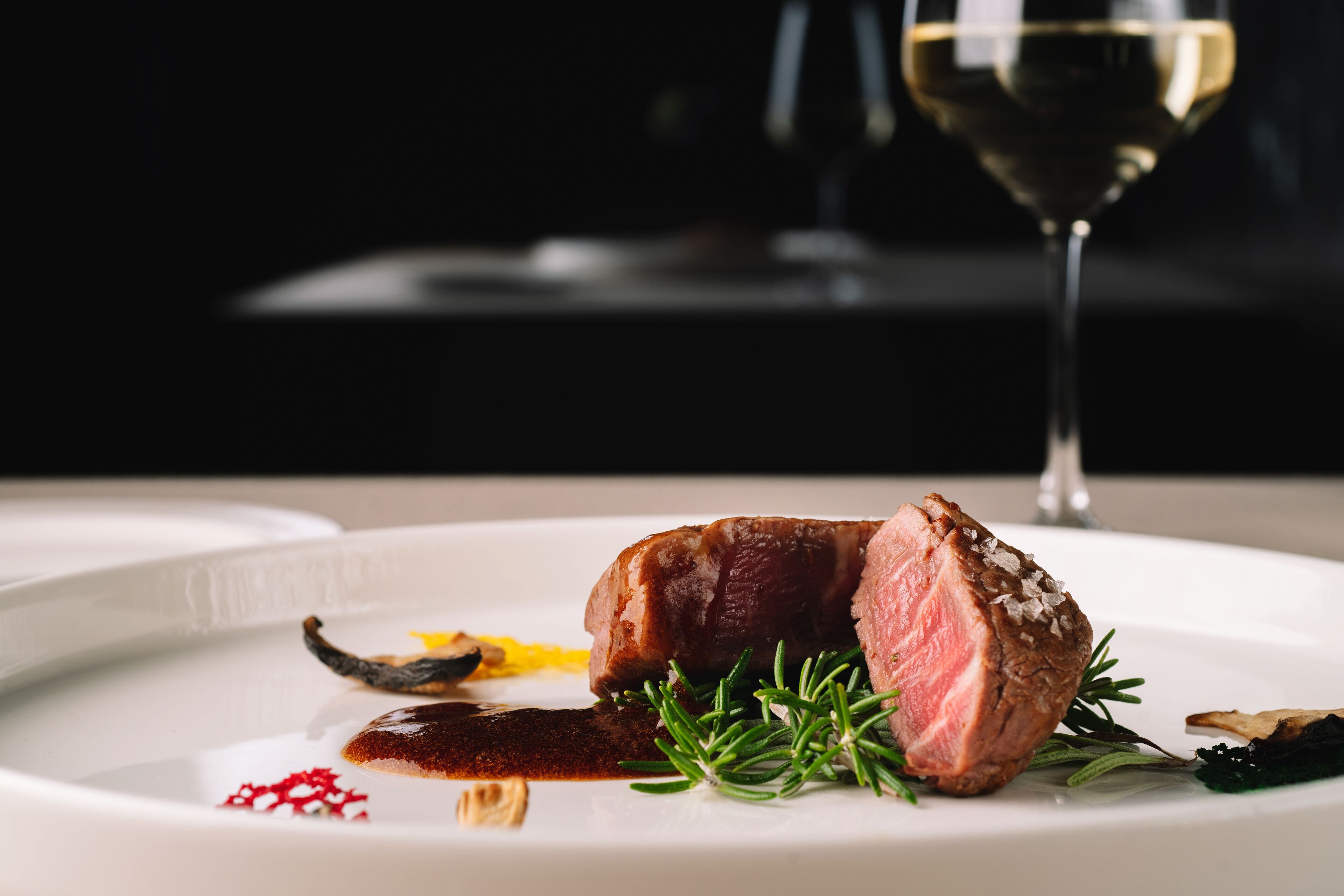 Un plato con una porción de carne, hierbas y salsa.
