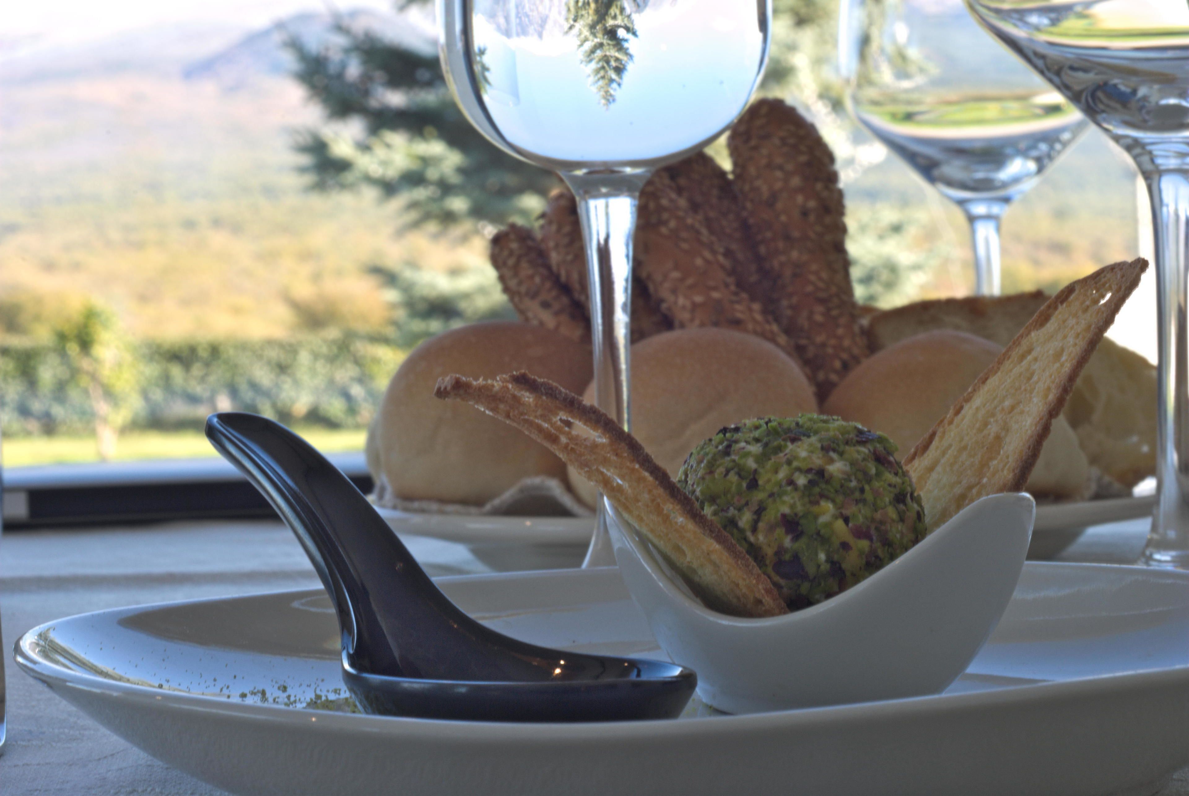 A table setting with a bowl of food, bread, and wine glasses.
