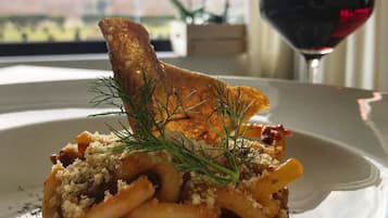 A plate of food with a glass of red wine and a scenic view in the background.