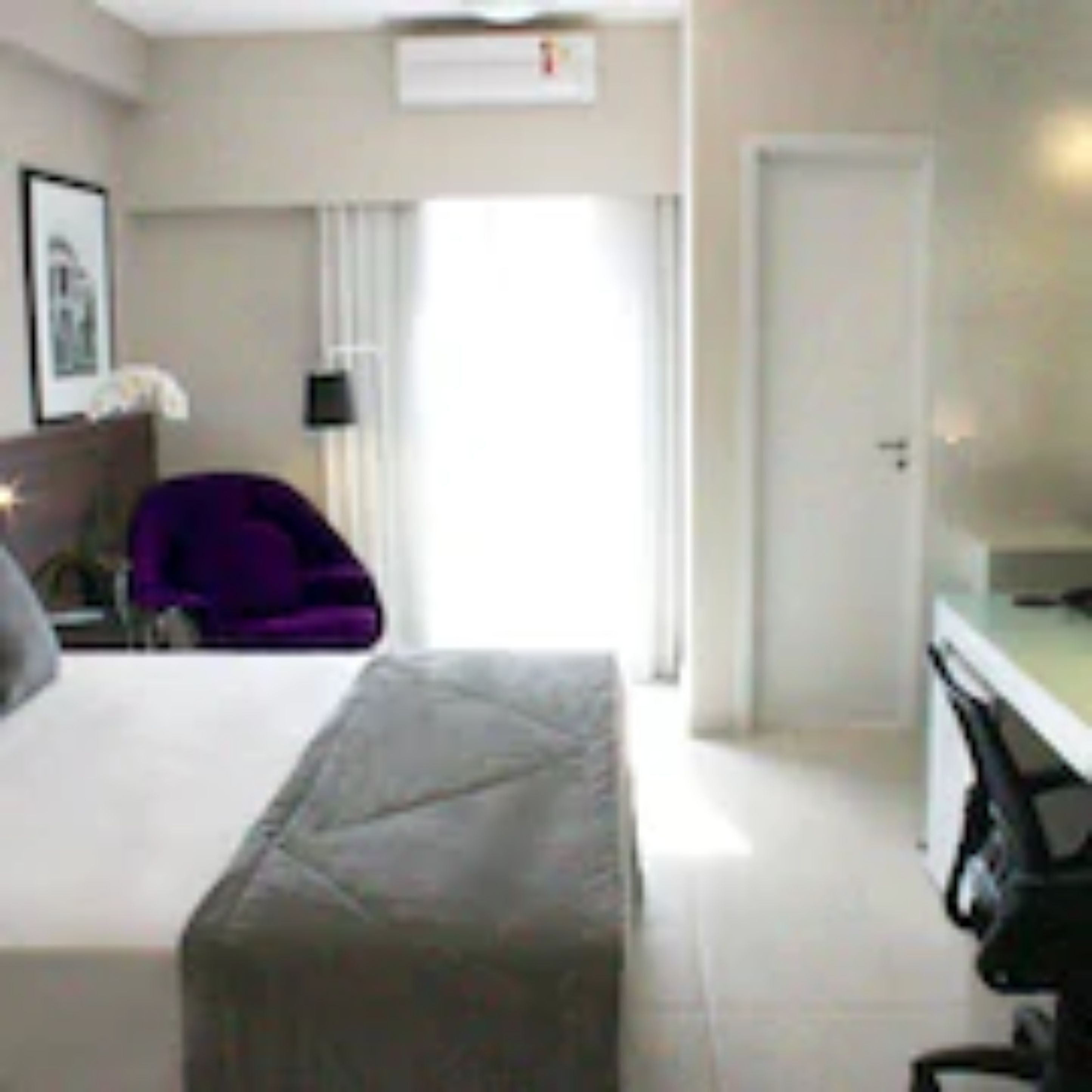 Una habitación de hotel con cama, escritorio, silla y puerta.