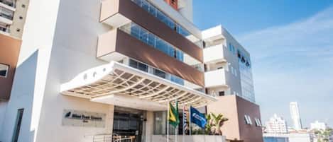 A modern hotel with a prominent entrance, multiple floors, and a covered outdoor area.