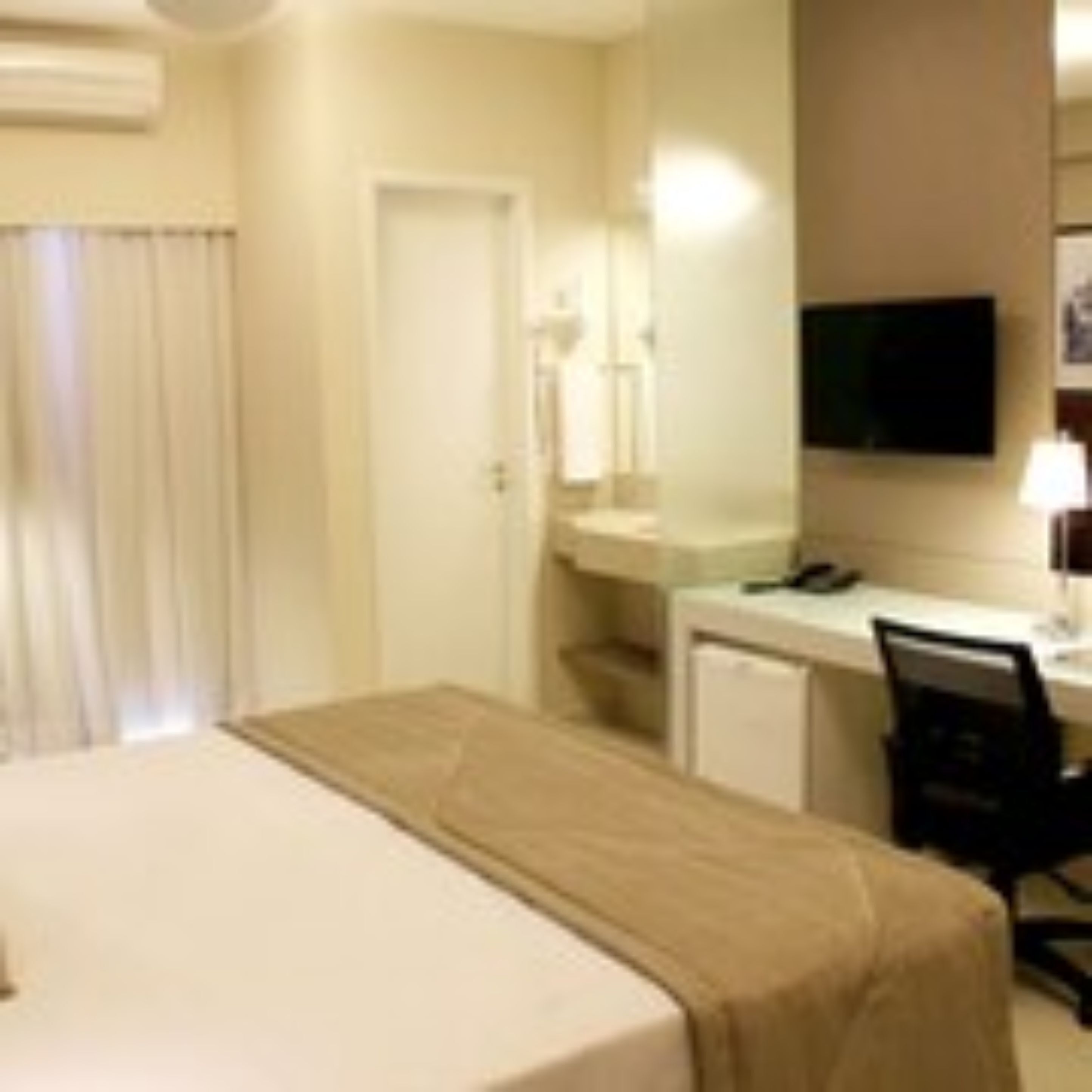 Habitación de hotel con cama, escritorio, silla, televisor y baño.