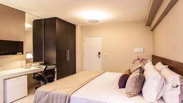 A hotel room with a bed, a desk with a chair, a television, and a door.