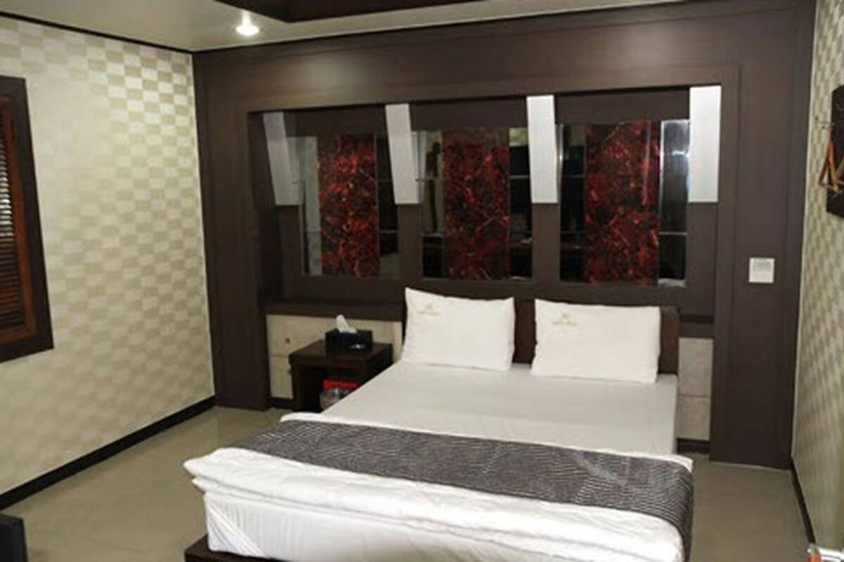 Un dormitorio con una cama grande, una mesita de noche, un espejo y una ventana con cortinas.
