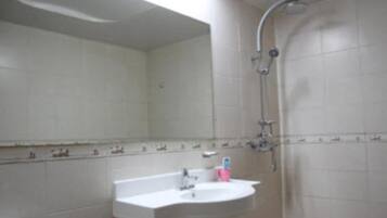 A bathroom with a white sink, a mirror, and a shower.